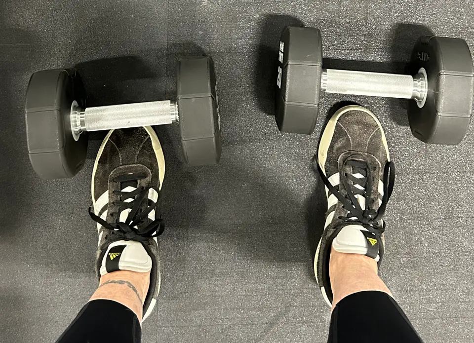 Working out with weights Close up of dumbbells in front of someone's black sneakers